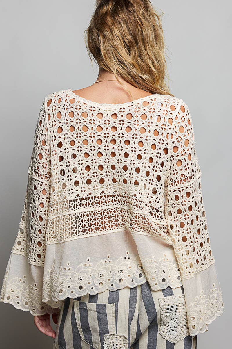 Model wearing The Briar Rose Crochet Blouse featuring intricate open crochet, embroidered eyelet cotton panels, long bell sleeves, and a relaxed bohemian silhouette in ivory.