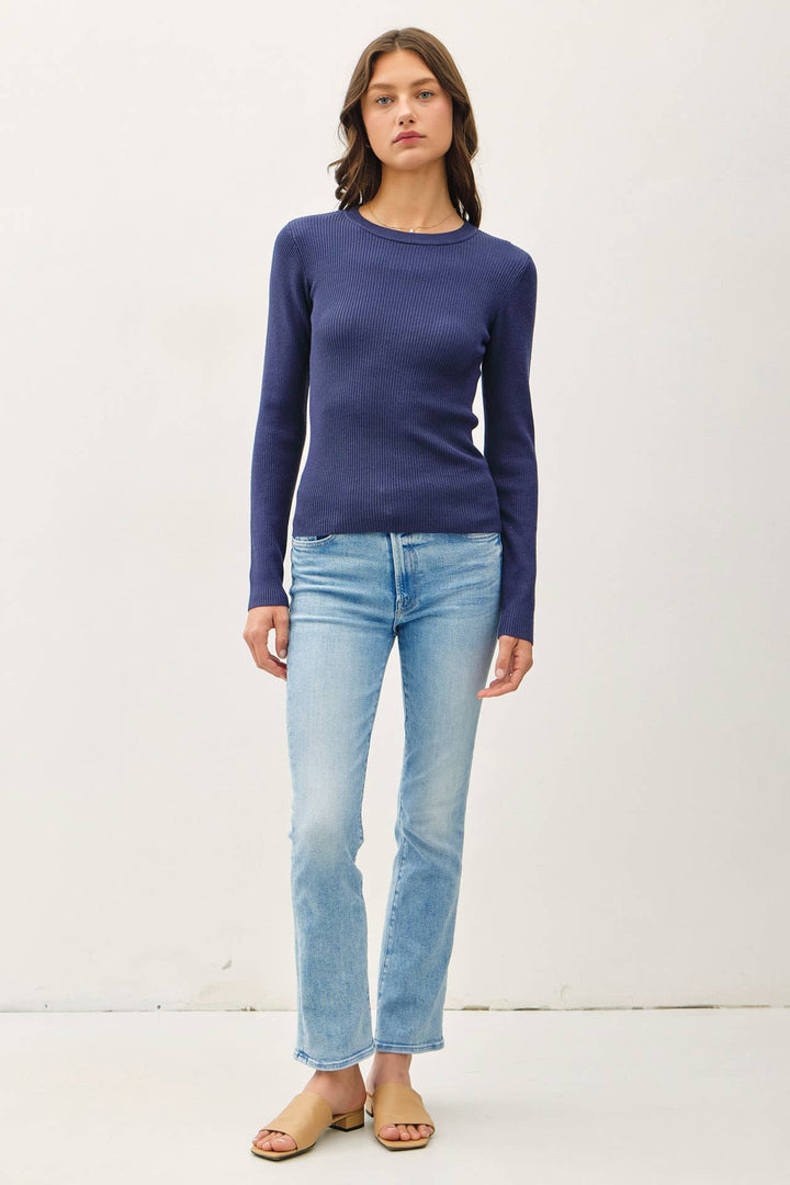 Woman wearing a blue long-sleeve top and light blue jeans on a white background