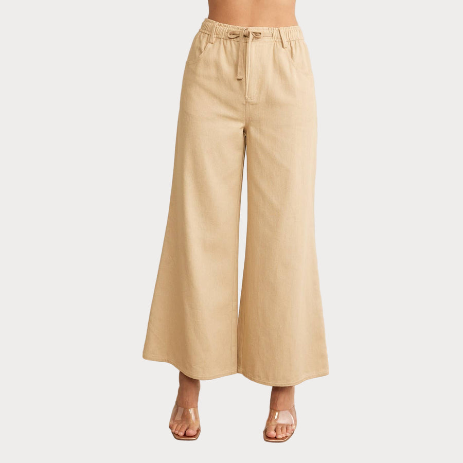 A female model wearing beige wide leg beige denim pants with an elastic waistband.
