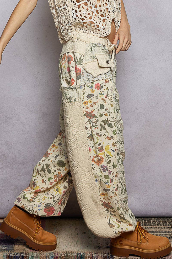 Model wearing The Cottage Bloom Patchwork Joggers by POL featuring vintage-inspired floral patchwork, textured jacquard details, oversized utility pockets, and a relaxed bohemian silhouette.