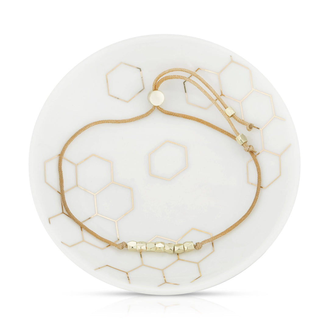 Gold bracelet on a white dish with honeycomb patterns