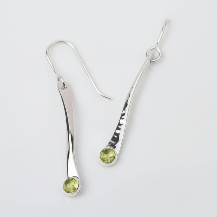 Silver earrings with green gemstones on a white background