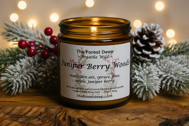 Candle jar labeled 'Juniper Berry Woods' with decorative elements on a wooden surface.