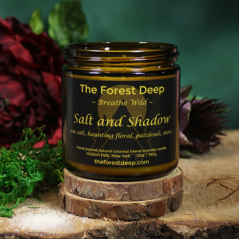 Candle jar labeled 'The Forest Deep' with decorative elements on a wooden surface.