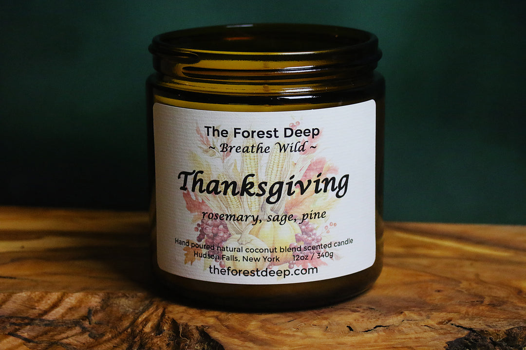 Amber glass candle labeled Thanksgiving with rosemary, sage, and pine notes
